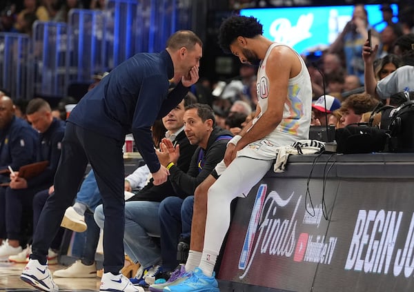 Denver Nuggets interim head coach David Adelman, left, confers with guard Jamal Murray as he sits on the scorer's table during a break in play in the first half of Game 6 in the Western Conference semifinals of the NBA basketball playoffs Thursday, May 15, 2025, in Denver. (AP Photo/David Zalubowski)