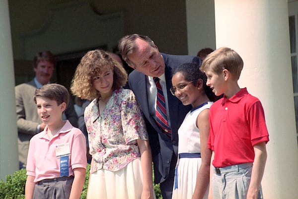 FILE - President George Bush meets with winners of the National Spelling Bee at the White House, May 31, 1991, including 13-year-old winner Joanne Lagatta, left, of Clintonville, Wisc., Maria Mathew, 11, of Sterling, Ill., and Todd Wallace, 13, of Blackfoot, Idaho. Boy at left is unidentified. (AP Photo/Barry Thumma, File)