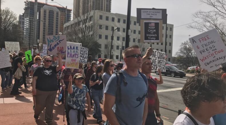 “Not My President’s Day” protesters walk up Peachtree St. on Monday. They say Donald Trump is unfit for the presidency. Photo: Christian Boone/AJC