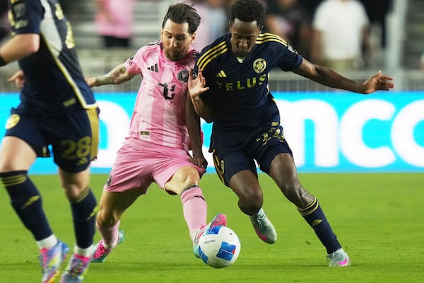 Inter Miami forward Lionel Messi, left, runs with the ball against Vancouver Whitecaps forward Ali Ahmed, right, during the first half of a CONCACAF Champions Cup second-leg semifinal soccer match, Wednesday, April 30, 2025, in Fort Lauderdale, Fla. (AP Photo/Lynne Sladky)
