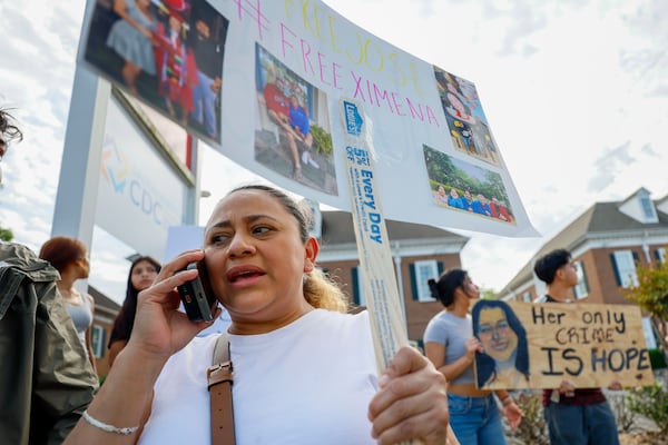 Ndahitha Cristobal speaks on the phone with her daughter Ximena Arias-Cristobal during a protest Wednesday. Although they speak on the phone every day, Cristobal is not sure how Ximena is coping with the conditions in the ICE jail. (Miguel Martinez/AJC)