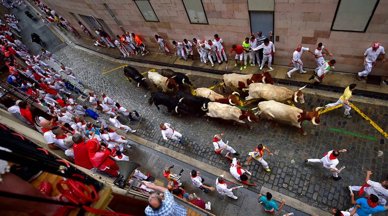 Revellers run next to Puerto de San Lorenzo's fighting bulls during the running of the bulls at the San Fermin Festival, in Pamplona, northern Spain, Saturday, July 7, 2018. Revellers from around the world flock to Pamplona every year to take part in the eight days of the running of the bulls. (AP Photo/Alvaro Barrientos)