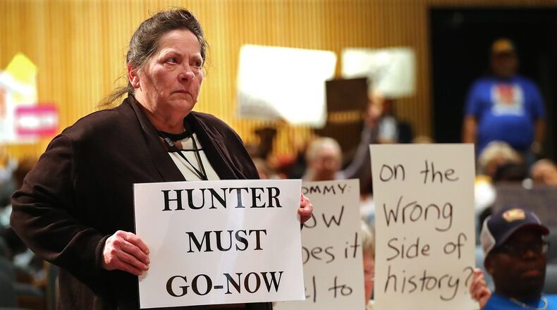 Collene Haskamp stands with her sign while more protesters demand the resignation of Tommy Hunter, the District 3 leader that recently called U.S. Rep. John Lewis a “racist pig” on Facebook, during the Gwinnett County Board of Commissioners public hearing Tuesday. Curtis Compton/ccompton@ajc.com