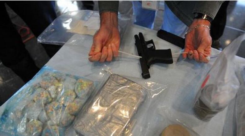 A law enforcement officer secures a handgun on display along with some of the 700,000 Ecstasy pills worth $2.8 million, left, and a kilo of cocaine seized in a drug raid.