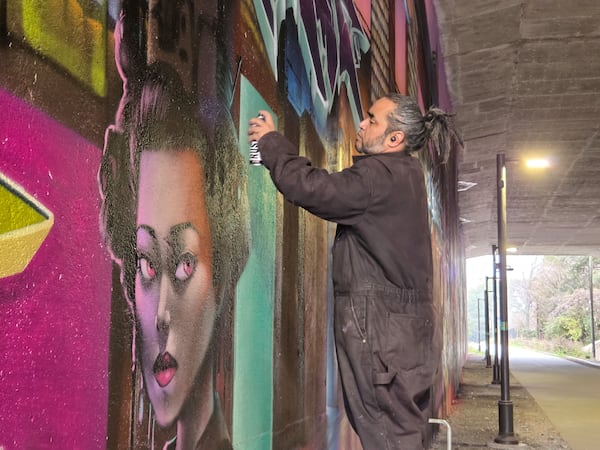 Mr. Totem works on a mural in progress along the Northeast Beltline trail. 
(Arthur Rudick)