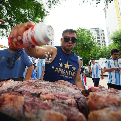 Lucas Martinez, of Dallas, an Argentina supporter, seasons meat with salt while grilling during a rally ahead of their team's World Cup Group J soccer match against Austria, Sunday, June 21, 2026, in Dallas. (AP Photo/Julio Cortez)