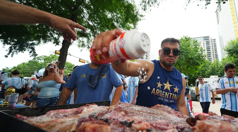 Lucas Martinez, of Dallas, an Argentina supporter, seasons meat with salt while grilling during a rally ahead of their team's World Cup Group J soccer match against Austria, Sunday, June 21, 2026, in Dallas. (AP Photo/Julio Cortez)