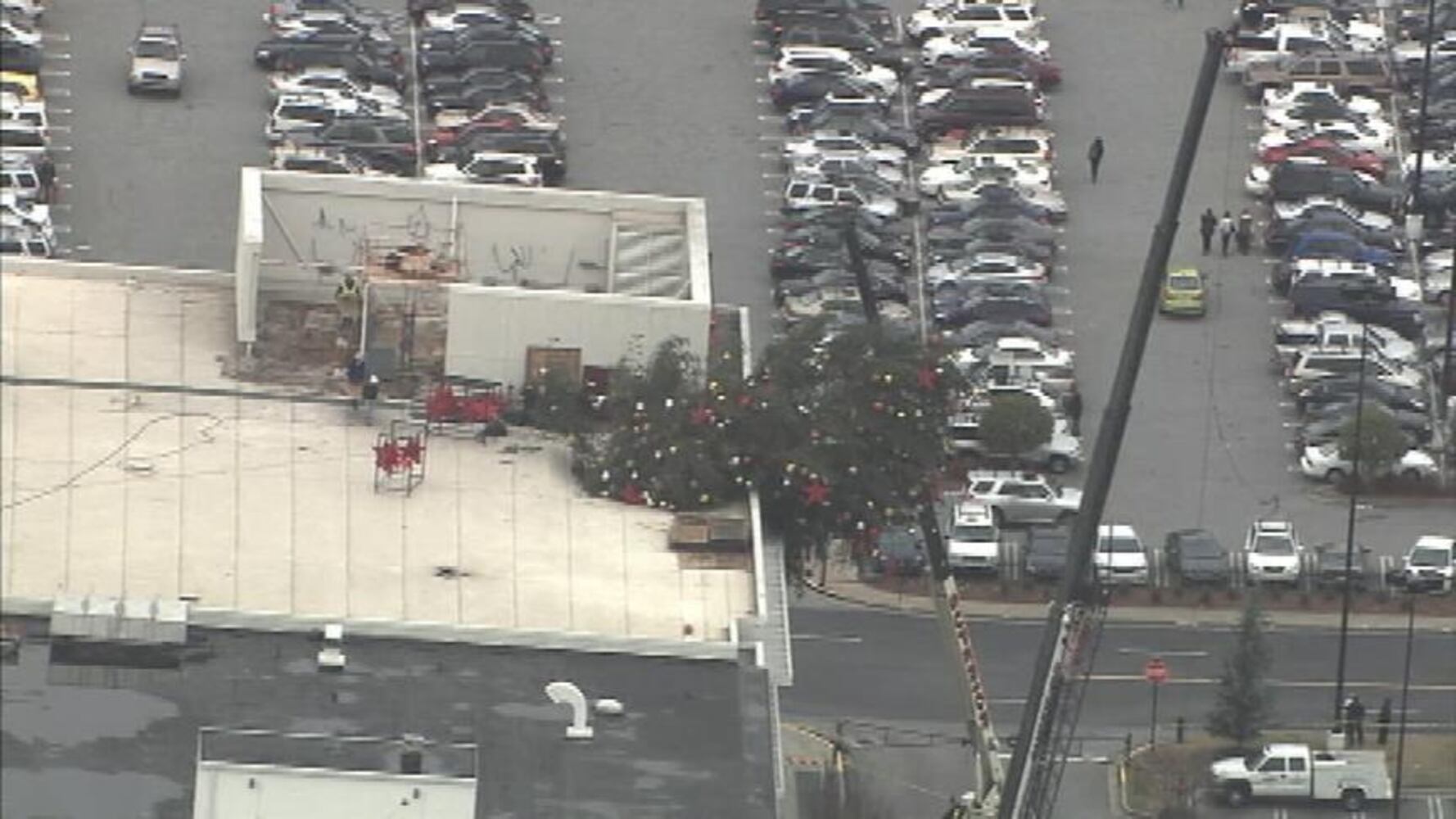 Crane buckles, leaving Christmas tree hanging off roof
