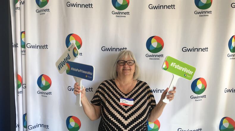 Mary Bowles, an advance voting clerk and Gwinnett County Department of Water Resources employee, displays some of the props that voters can use at advance voting selfie stations.