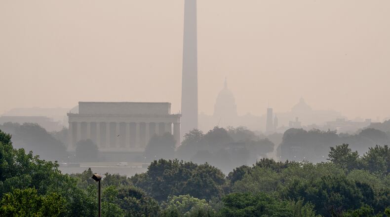 The Lincoln Memorial, the Washington Monument, and the U.S. Capitol, are barely visible from an overlook in Arlington, Va., as heavy smoke from wildfires shrouds the landscape in Washington, Friday, July 17, 2026. (AP Photo/J. Scott Applewhite)
