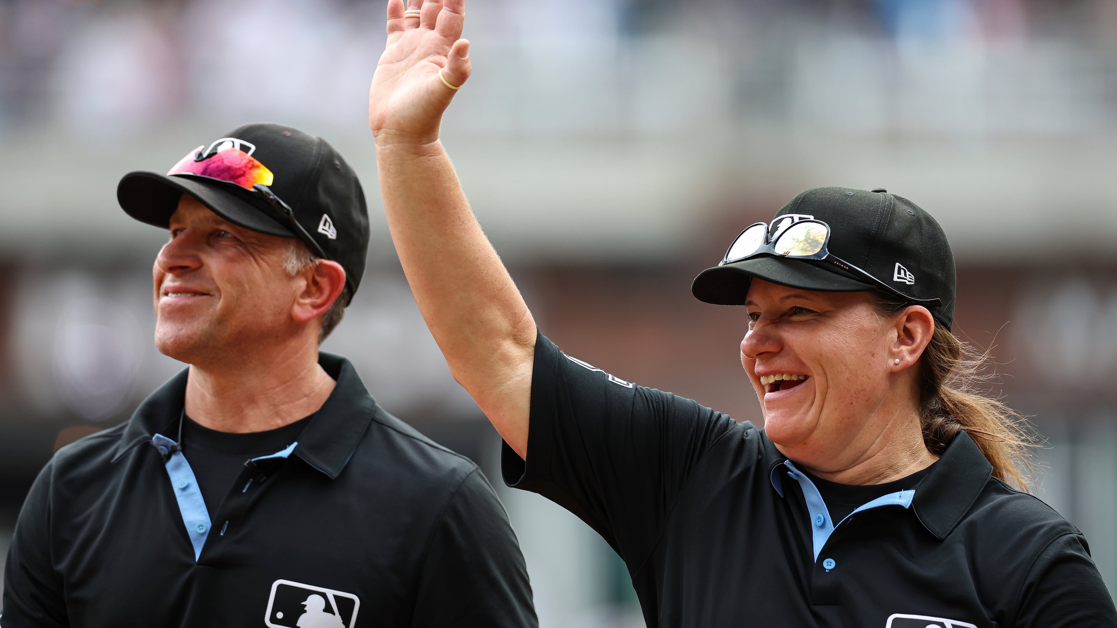 Umpires Chris Guccione, left, and Jen Pawol, right, react to fans in the crowd at the conclusion of the first baseball game of a doubleheader between the Atlanta Braves and Miami Marlins, Saturday, Aug. 9, 2025, in Atlanta. (AP Photo/Colin Hubbard)