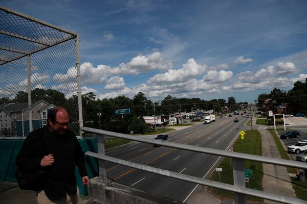 A man walks across an uncovered pedestrian crossing over Highway 21 in Garden City.