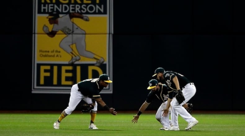Oakland Athletics' Khris Davis, left, Jaff Decker, center, and Matt Joyce celebrate after the team's 3-1 win over the Seattle Mariners in a baseball game Friday, April 21, 2017, in Oakland, Calif. (AP Photo/Marcio Jose Sanchez)