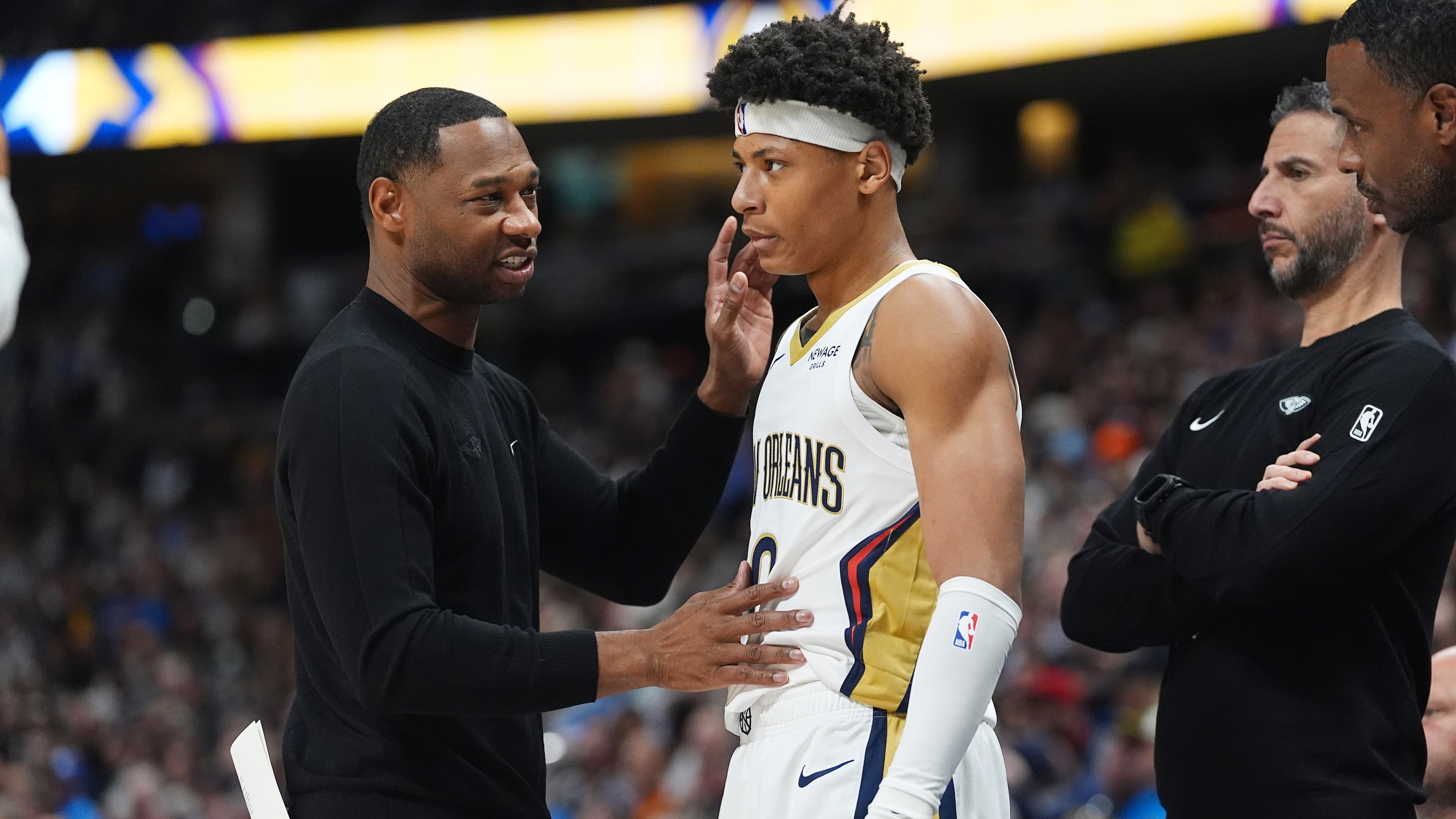 New Orleans Pelicans head coach Willie Green, left, confers with guard Jeremiah Fears, center, as assistant coach James Borrego looks on in the first half of an NBA basketball game against the Denver Nuggets Wednesday, Oct. 29, 2025, in Denver. (AP Photo/David Zalubowski)