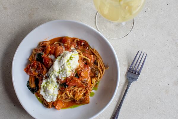 A plate of tomato pasta topped with white, creamy burrata.