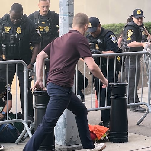 In this photo provided by Robert Sullivan several officers surround a person on the ground near the site of a fire at 26 Federal Plaza in lower Manhattan, Monday, July 20, 2026, in New York. (Robert Sullivan via AP)