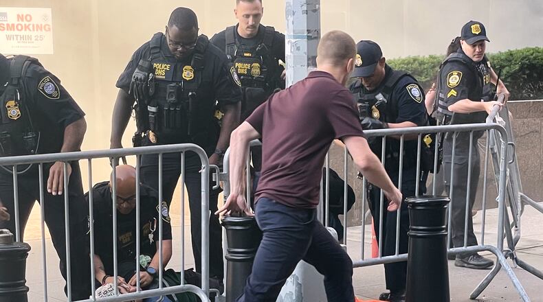 In this photo provided by Robert Sullivan several officers surround a person on the ground near the site of a fire at 26 Federal Plaza in lower Manhattan, Monday, July 20, 2026, in New York. (Robert Sullivan via AP)