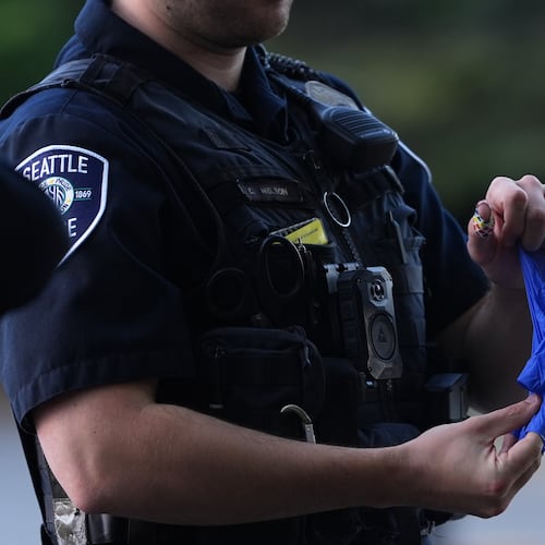 A police officer puts a bullet casing into a rubber glove after he received it from a person who found it, following a shooting at Seattle Center during the Bite of Seattle food festival, Monday, July 27, 2026, in Seattle. (AP Photo/Lindsey Wasson)