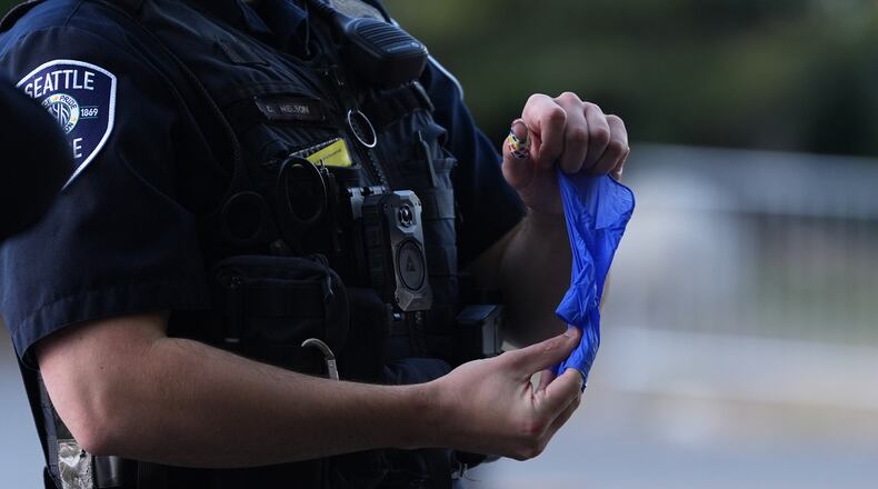 A police officer puts a bullet casing into a rubber glove after he received it from a person who found it, following a shooting at Seattle Center during the Bite of Seattle food festival, Monday, July 27, 2026, in Seattle. (AP Photo/Lindsey Wasson)