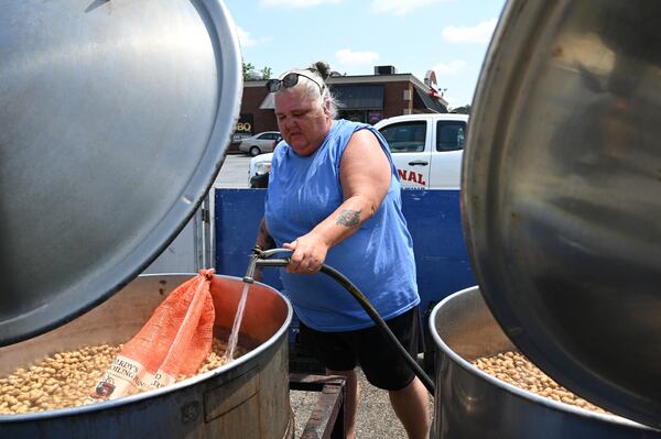Timmi Moore adds some water as she warms up peanuts in a steam kettle at one of Hardy Farms’ roadside stands in Warner Robins.  (Hyosub Shin/AJC)