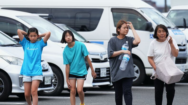 People arrive at the Hikawa Town Hall to receive food and water supplies in Hikawa, southern Japan, Thursday, July 30, 2026, two days after an earthquake hit the area. (AP Photo/Hiro Komae)