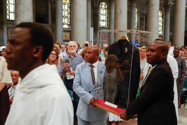 The jacket that Floribert Bwana Chui Bin Kositi was wearing at the time of his assassination is carried as a relic by his brothers Jean-Claude, left, and Trésor, at the start of a ceremony for his beatification in St. Paul Outside the Walls' Basilica, in Rome, Sunday, June 15, 2025. (AP Photo/Riccardo De Luca)