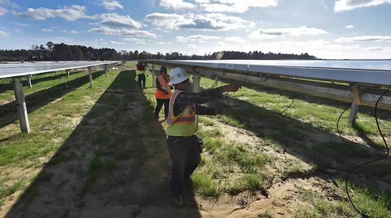 Workers with Solar Panel Solutions install solar panels in February in Bronwood, Ga., in the southern part of the state. HYOSUB SHIN / HSHIN@AJC.COM