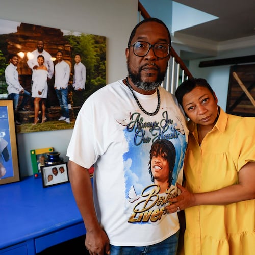 Ramonne and Terrica Thomas stand in the living room of their Mableton home, surrounded by images of their son, Boston Thomas, who was killed in May 2024 when a Cobb County police officer used a PIT maneuver to end a high-speed chase. The parents have filed a lawsuit against the county. (Miguel Martinez/AJC)