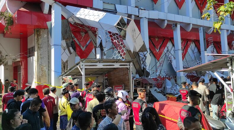 Onlookers gather as police officers inspect a damaged building following an earthquake in Manado, North Sulawesi, Indonesia, Thursday, April 2, 2026. (AP Photo/Tonny Rarung)
