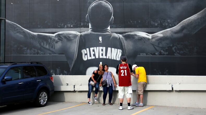 Cleveland Cavalier fans Teig Colgrove, left, and Sayeh Ashley, center, of Akron, take a selfie in front of a mural of Cleveland Cavaliers' LeBron James outside the Quicken Loans Arena early Wednesday, June 22, 2016 while waiting for a parade celebrating the Cleveland Cavaliers' NBA Championship through downtown Cleveland. (AP Photo/Gene J. Puskar)