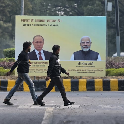 Men walk past a billboard with portraits of Indian Prime Minister Narendra Modi, right, and Russian President Vladimir Putin, hours before the scheduled arrival of the latter in New Delhi, India, Thursday, Dec. 4, 2025. (AP Photo)