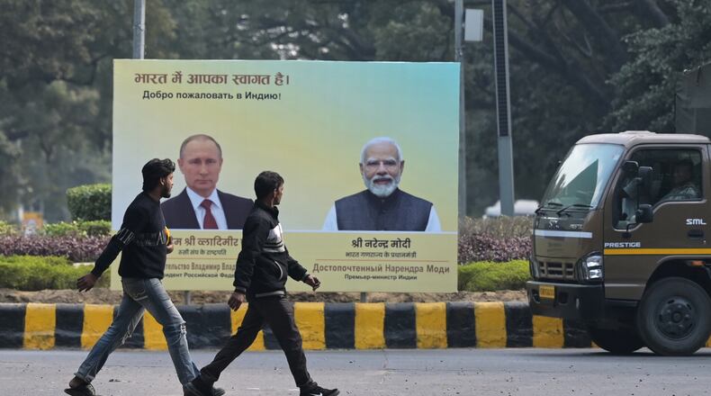 Men walk past a billboard with portraits of Indian Prime Minister Narendra Modi, right, and Russian President Vladimir Putin, hours before the scheduled arrival of the latter in New Delhi, India, Thursday, Dec. 4, 2025. (AP Photo)