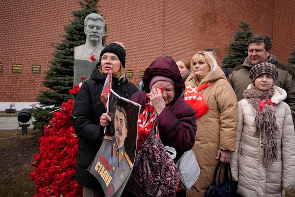 FILE - An elderly woman cries while holding a portrait of Soviet leader Josef Stalin after laying flowers at his grave near the Kremlin Wall in Red Square in Moscow on Wednesday, March 5, 2025, to mark the 72nd anniversary of his death. (AP Photo/Alexander Zemlianichenko, File)
