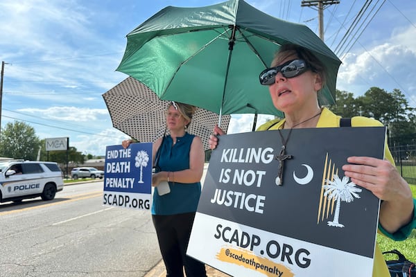 Protesters shielding themselves in the 84-degree heat await the planned execution of Stephen Stanko outside the Broad River Road Correctional Institution in Columbia, S.C., on Friday, June 13, 2025. (AP Photo/Allen G. Breed)