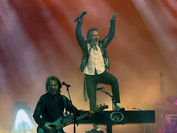 Styx keyboardist and vocalist Lawrence Gowan, part of the band since 1999, steps on his piano during "Come Sail Away" while his brother Terry Gowan, looks on during their concert at Ameris Bank Amphitheatre in Alpharetta on Sunday. (Rodney Ho/AJC)