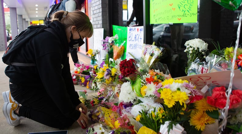 Shelby Swan rearranges flowers at a memorial during a candlelight vigil to honor the lives of those killed at Youngs Asian Massage in March.