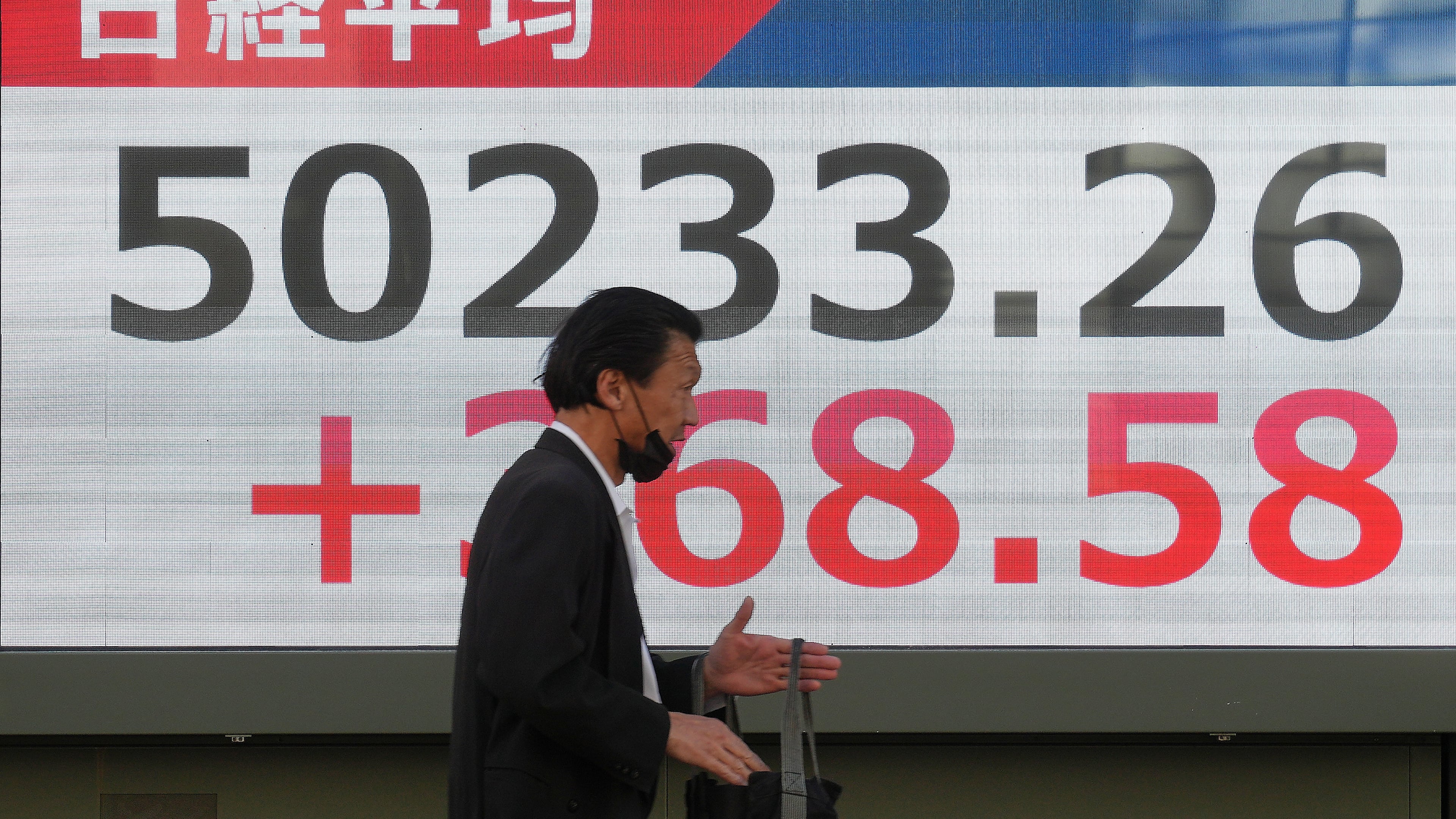A person walks in front of an electronic stock board showing Japan's Nikkei index at a securities firm Thursday, Dec. 4, 2025, in Tokyo. (AP Photo/Eugene Hoshiko)