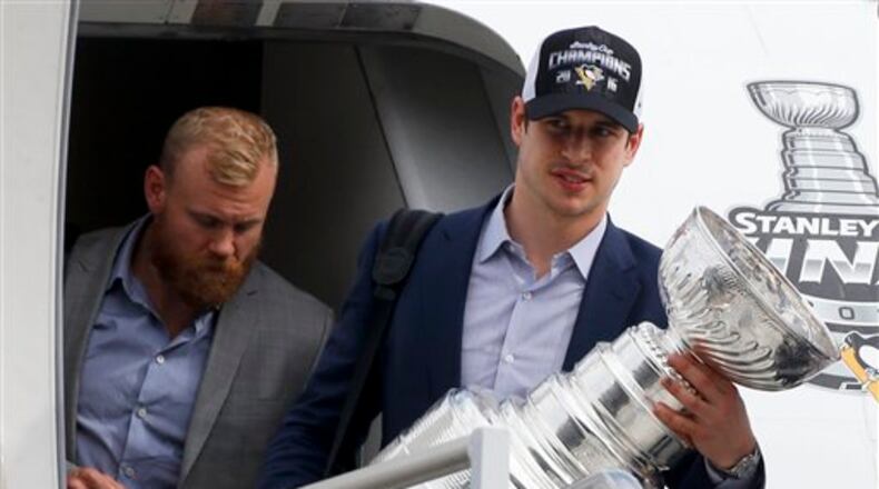 Pittsburgh Penguins' Sidney Crosby, right, gets off the jet from California with the Stanley Cup beside Patric Hornqvist after the team arrived to a private hangar at Greater Pittsburgh International Airport in Moon, Pa., Monday, June 13, 2016. The Penguins defeated the San Jose Sharks on Sunday to win the NHL hockey championship. (AP Photo/Keith Srakocic)