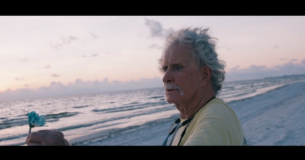 Steve Lamb admires a flower at sunset on the beach during the filming of "The Green Flash," a documentary that examines his end-of-life reflections as he retells the story of having been a legendary teenage marijuana smuggler. (Courtesy of "The Green Flash")