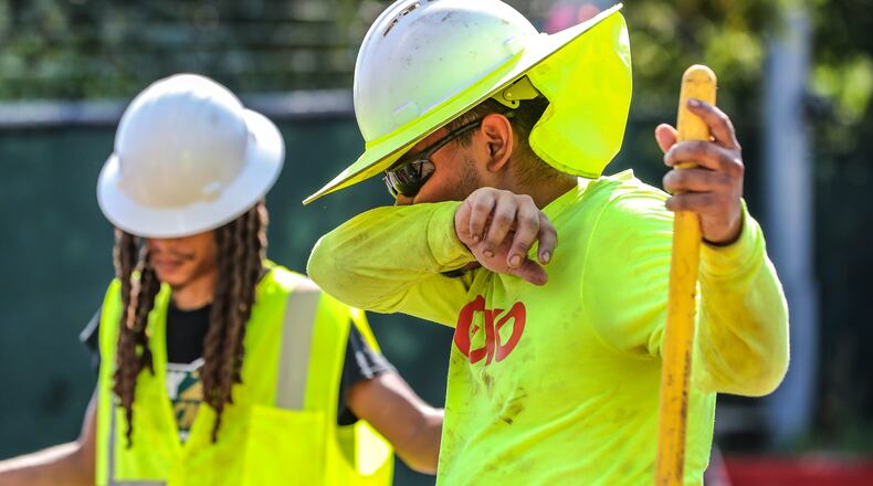 Electrical contractors installing an electrical box on Aug. 14 on Northside Drive near Interstate 75 in Atlanta. The area was experiencing  oppressive heat. (John Spink/The Atlanta Journal-Constitution)