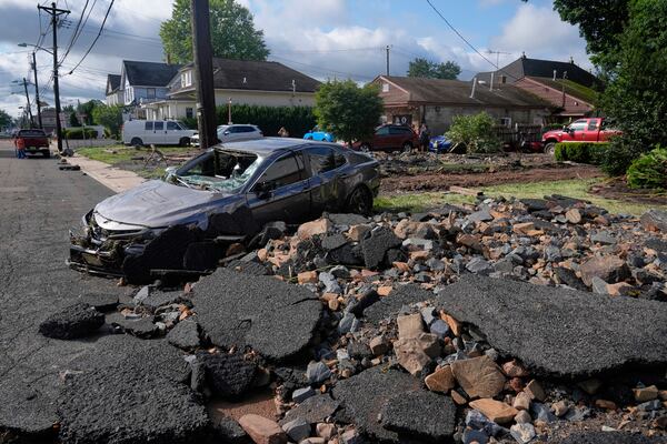 Debris, rubble and a damaged car lie on a street after flooding from rains in the area in North Plainfield, N.J., Tuesday, July 15, 2025. (AP Photo/Seth Wenig)