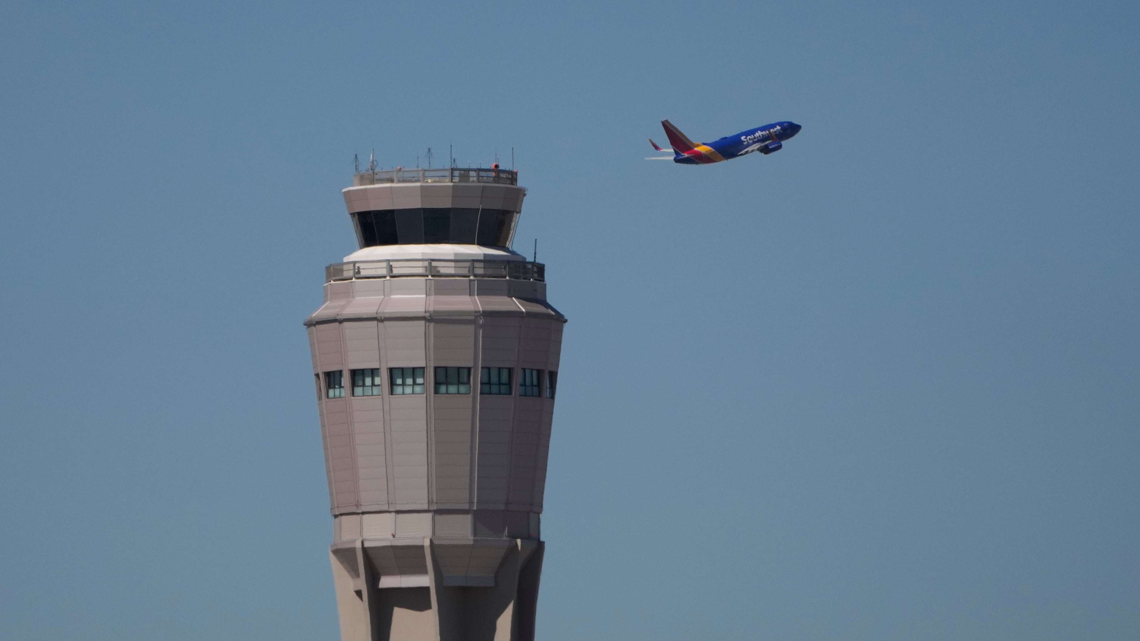 A plane takes off near the air traffic control tower at Harry Reid International Airport, Tuesday, Oct. 7, 2025, in Las Vegas. (AP Photo/John Locher)