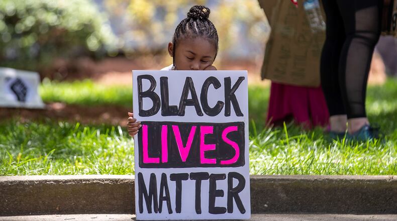Corri Griffith, 5, takes a rest as she and her father Corey Griffith, who was close by, listen to demonstrators speak during a rally near the steps of Atlanta City Hall during the fourth day of protests in Atlanta, Monday, June 1, 2020. Corri and her father created the Black Lives Matter sign that she held during the rally. (ALYSSA POINTER / ALYSSA.POINTER@AJC.COM)