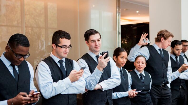 Wait staff at the Modern use their phones to participate in a text-message poll regarding satisfaction with the restaurant’s new no-tipping policy, in New York, Nov. 10, 2015. Danny Meyer’s restaurant empire is phasing out tipping, beginning with this location at the Museum of Modern Art.