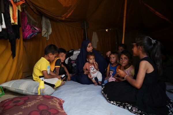 Maryam Abu Shaar, 29, sits with her children inside their tent at a camp for displaced Palestinians in Mawasi Khan Younis, Gaza Strip, on the first day of Eid al-Adha, Friday, June 6, 2025. (AP Photo/Abdel Kareem Hana)