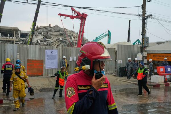 A rescuers talks on his walkie-talkie as heavy machineries are employed to clear the huge pile of concrete at an under-construction high-rise building that collapsed after an earthquake in Bangkok, Thailand, Tuesday, April 1, 2025. (AP Photo/Manish Swarup)