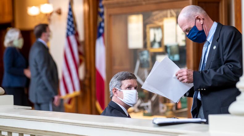 Jim Potvin, center, the executive director of the Employees’ Retirement System, and L. C. “Buster” Evans, the executive director of the Teachers Retirement System, go over notes as they wait to be called to speak to Senate budget writers. (ALYSSA POINTER / ALYSSA.POINTER@AJC.COM)