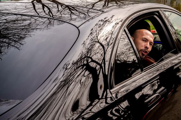Andrew Tate speaks to media as he leaves in a vehicle after checking in at a police station as part of his judicial control, which requires him to appear before judicial authorities in Romania when summoned, in Voluntari, Romania, Monday, March 24, 2025. (AP Photo/Vadim Ghirda)