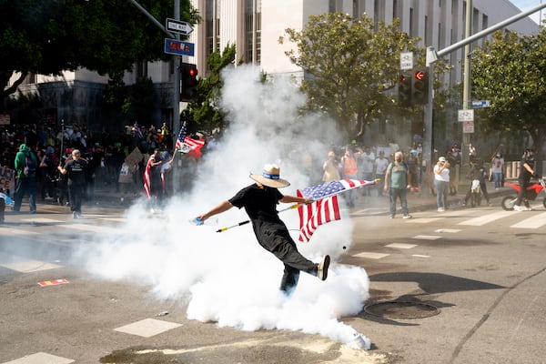 A demonstrator kicks a canister of tear gas during a protest Saturday, June 14, 2025, in Los Angeles. (AP Photo/Noah Berger)