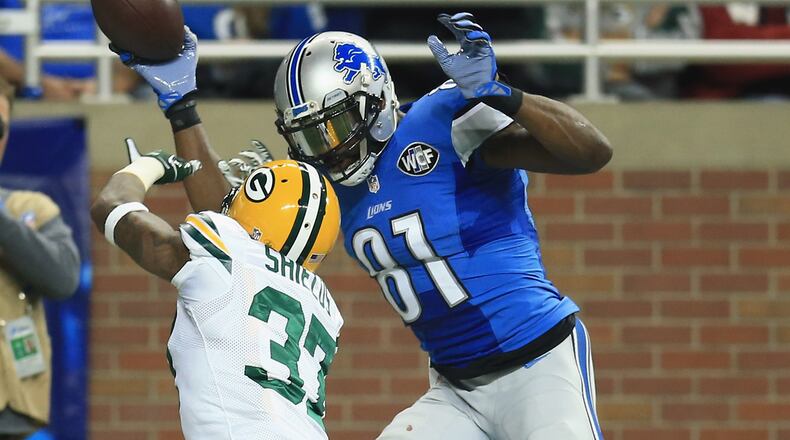 Before taking early retirement, Detroit's Calvin Johnson towers over and toys with a Green Bay defender. (Andrew Weber/Getty Images)